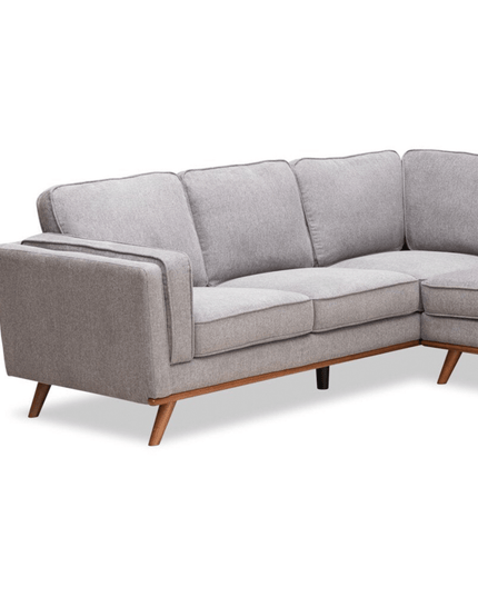 The Maddox LSF is a gray mid-century modern sectional with an L-shaped design and wooden legs. It offers plush back and seat cushions, while the soft, slightly textured fabric is ideal for enhancing a minimalist or contemporary living space.