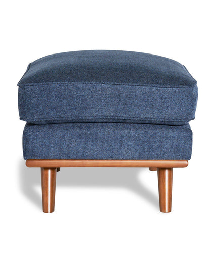 The Maddox Ottoman features a rectangular cushion in blue upholstery and rests elegantly on wooden legs, casting a shadow against a white background—ideal for adding mid-century charm to any living space.