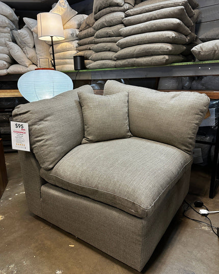 The 1 Piece My Cloud Corner Chair in Bark, made from discontinued fabric, is on sale for $95. Displayed with pillows on shelves and lit by a lamp with a blue shade, only one of this limited edition model is available—dont miss out!.