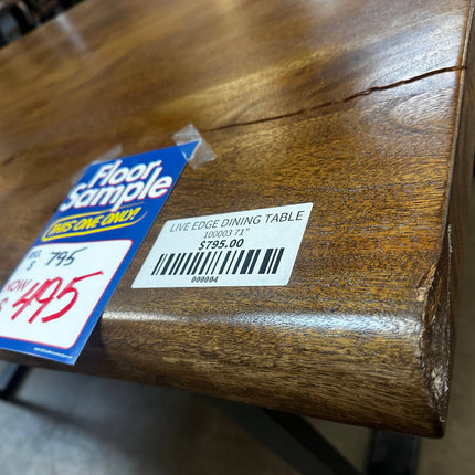 Close-up of a wooden dining table labeled Live Edge Dining Table 71 / Damaged Corner. It displays price info: Floor Sample, Was $795, Now $495, highlighting a natural finish and a visible crack as part of an impressive woodworking project.