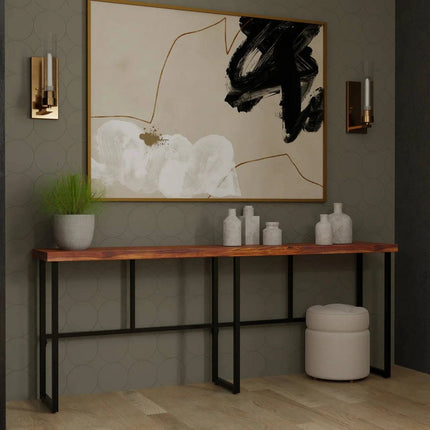 A modern interior features the Rosewood Console with black metal legs. Decorative vases and a potted plant adorn it, while an abstract black, white, and gold painting hangs above. Wall sconces flank the artwork, and a round stool below completes the dining room furniture aesthetic.